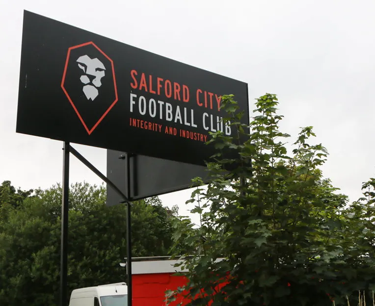 Biển hiệu 'Salford City FC' nổi bật tại sân Moor Lane, chào đón người hâm mộ.