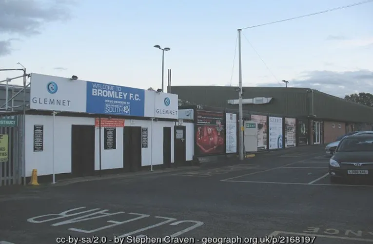 Cổng ngoài của Sân vận động Hayes Lane, mang vẻ cổ kính và thân thiện, chào đón người hâm mộ Bromley FC