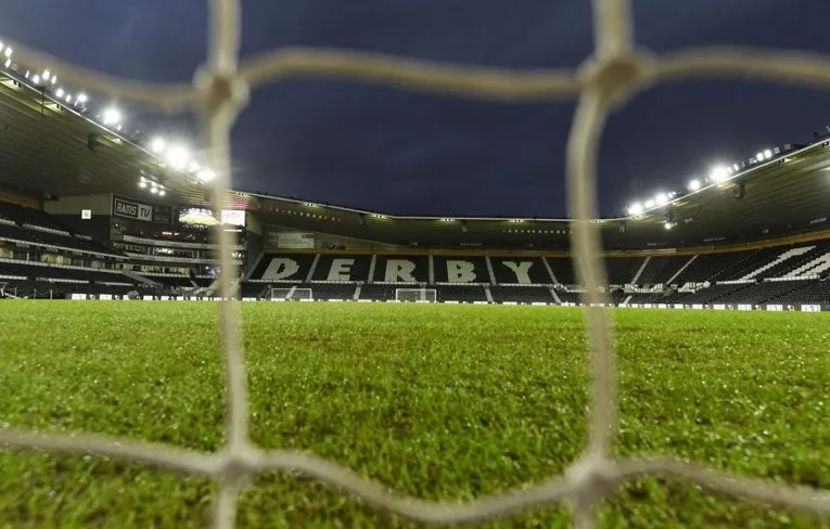 Góc nhìn độc đáo sân vận động Pride Park qua khung lưới gôn, cho thấy toàn cảnh sân và khán đài từ một góc độ mới lạ.