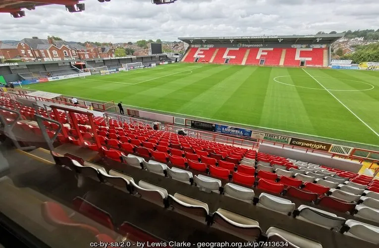 Góc nhìn toàn cảnh sân cỏ St. James Park Exeter từ khán đài, cho thấy chất lượng mặt sân và không khí chờ đợi trận đấu.
