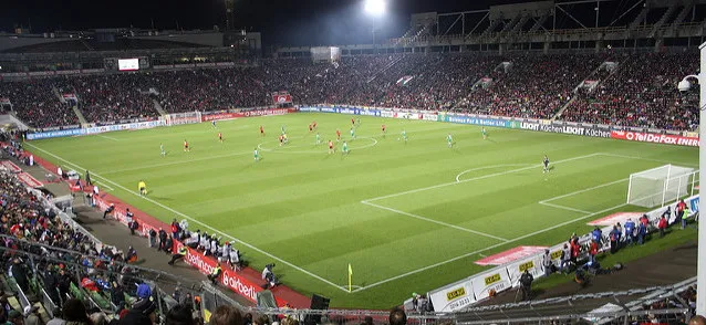 Góc nhìn từ khán đài trên cao xuống sân BayArena, với ánh đèn pha chiếu sáng mặt cỏ