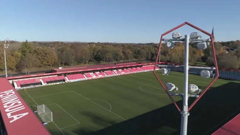 Hệ thống đèn pha chiếu sáng tại sân Peninsula Stadium vào buổi tối, biểu tượng của các trận đấu bóng đá kịch tính.