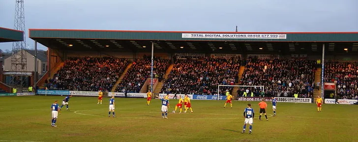 Khoảnh khắc trận đấu kịch tính giữa Rochdale và Darlington trên sân nhà Spotland, với sự cổ vũ cuồng nhiệt của khán giả.