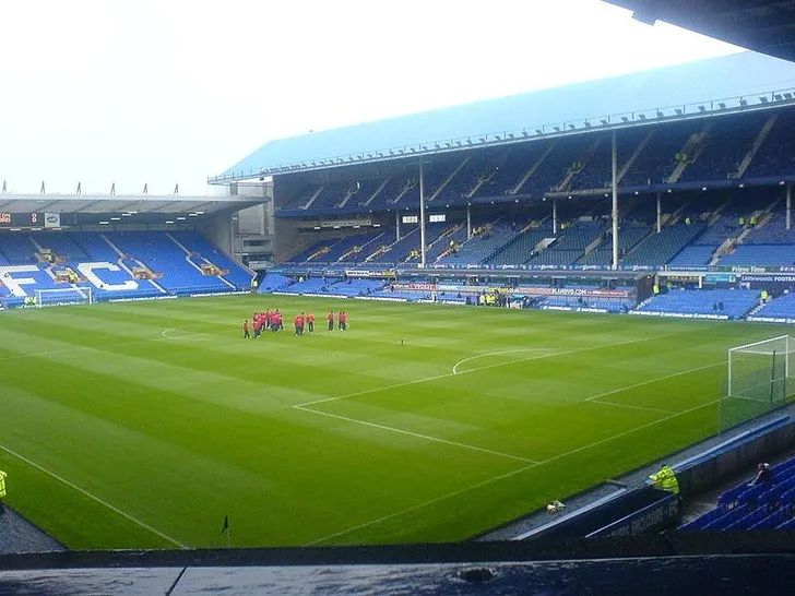 Khung cảnh bên trong sân Goodison Park nhìn từ khán đài, với cỏ xanh mướt và kiến trúc gần gũi với mặt sân