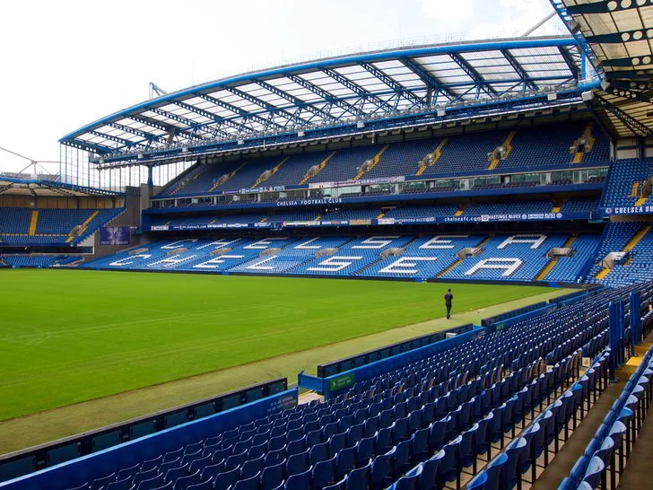 Khung cảnh bên trong sân Stamford Bridge với hàng ghế xanh đặc trưng và mặt cỏ xanh mướt, sẵn sàng cho các trận đấu đỉnh cao