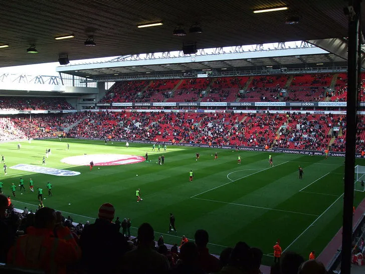 Khung cảnh bên trong sân vận động Anfield nhìn ra mặt cỏ xanh mướt và các khán đài chính, thể hiện không khí hùng vĩ của sân nhà Liverpool FC.