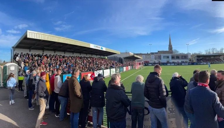 Khung cảnh sân vận động Meadowbank của Dorking Wanderers vào ngày thi đấu, đông đúc người hâm mộ tạo nên bầu không khí sôi động và náo nhiệt.